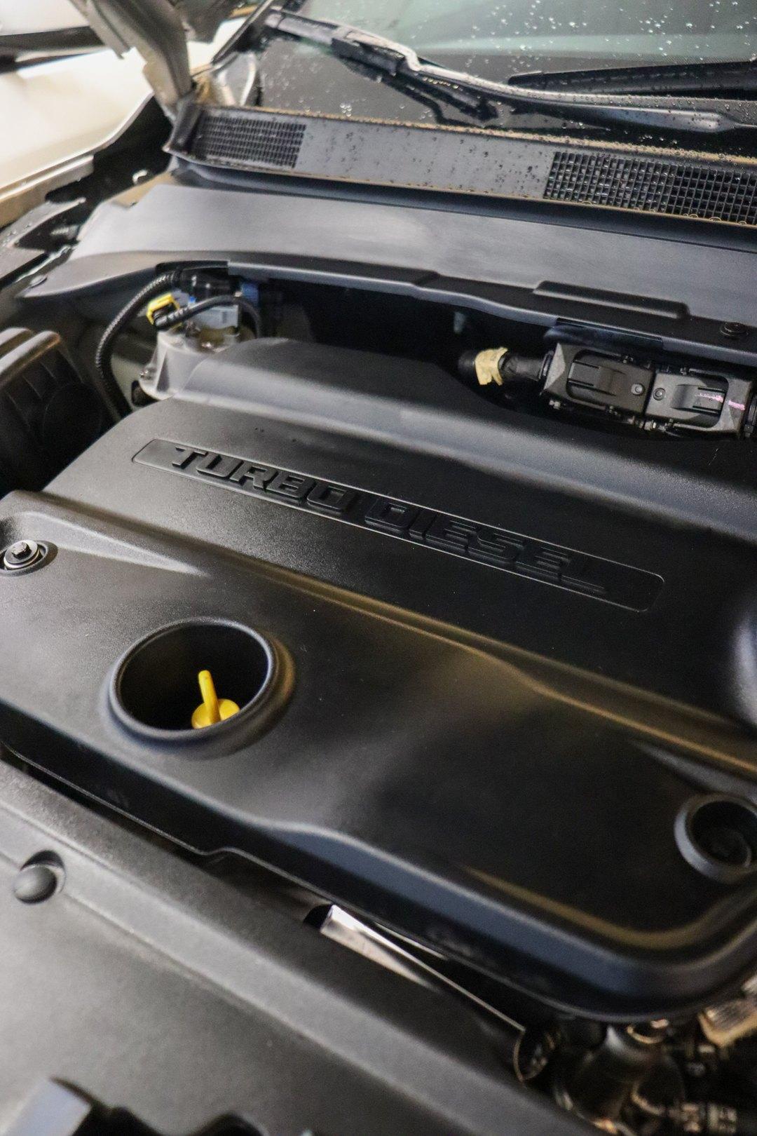 Compartimento do motor com o capô aberto, mostrando a capa plástica preta com a inscrição Turbo Diesel e a vareta de óleo amarela