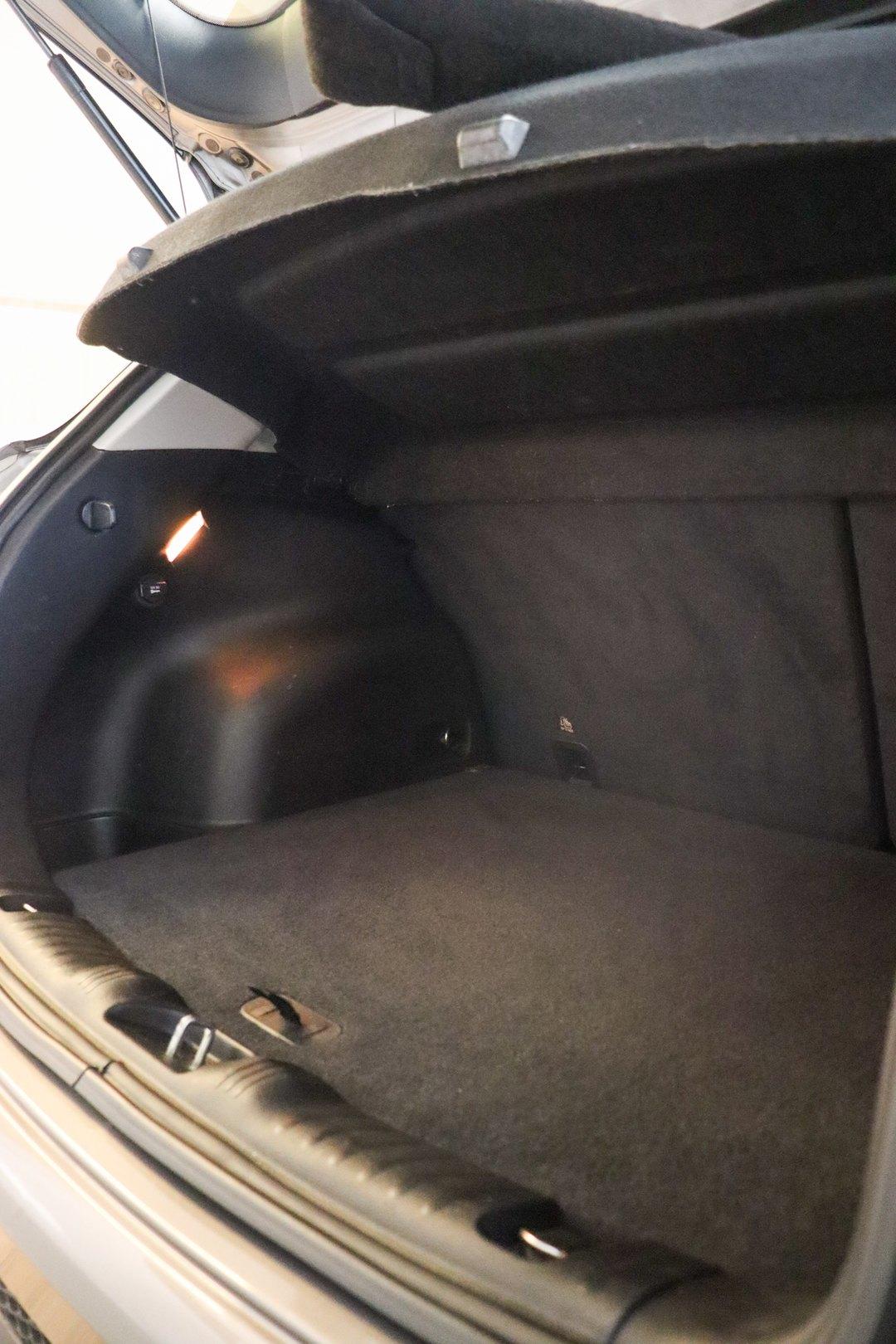 Porta-malas aberto de um hatch prateado, com carpete escuro, tampão erguido e luz interna acesa