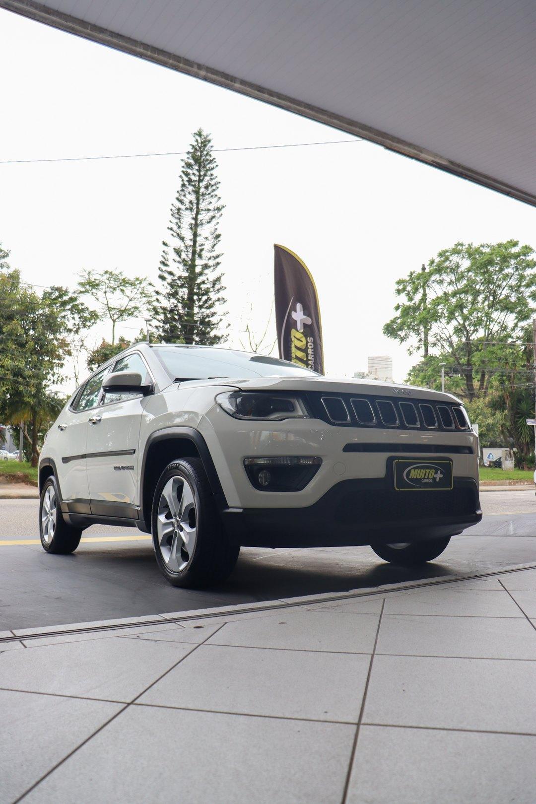 Jeep Compass branco, SUV médio, na entrada coberta da Muito Mais Carros em São José